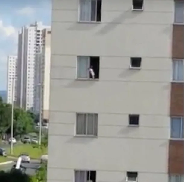 Toddler seen at open third-story window of an apartment building.
