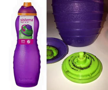 Purple Sistema Twist 'n' Sip bottle with orange lid; green cap removed showing black residue on components.