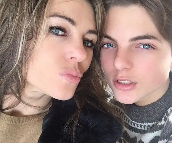 Two individuals with similar blue eyes pose closely, smiling softly, showcasing their resemblance.