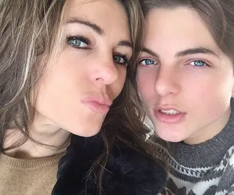 Two individuals with similar blue eyes pose closely, smiling softly, showcasing their resemblance.