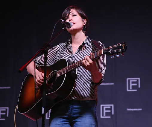 Singer performing on stage with a guitar.