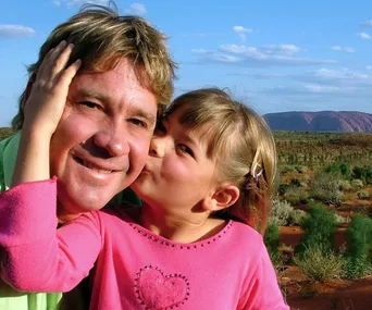 Father and daughter share a joyful moment in a scenic desert landscape.