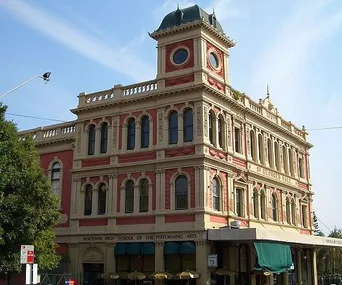 Historic red and beige three-story building with ornate windows, identified as Newtown High School of the Performing Arts.