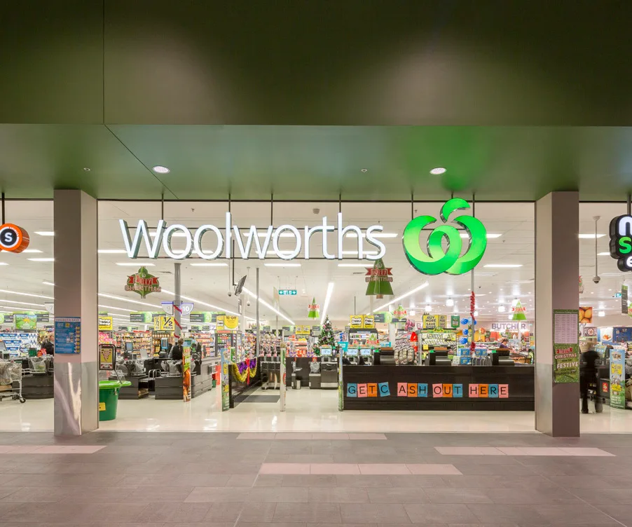 Exterior view of a Woolworths store entrance with bright signage and interior displays.