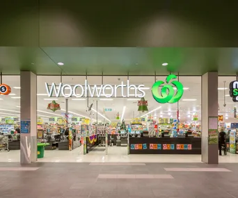 Exterior view of a Woolworths store entrance with bright signage and interior displays.