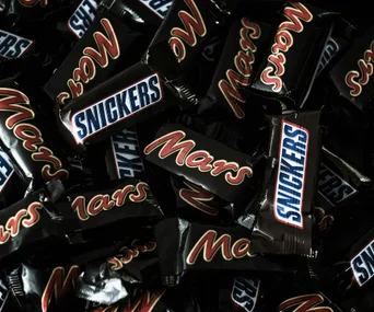 Mars and Snickers chocolate bars in black wrappers piled together.