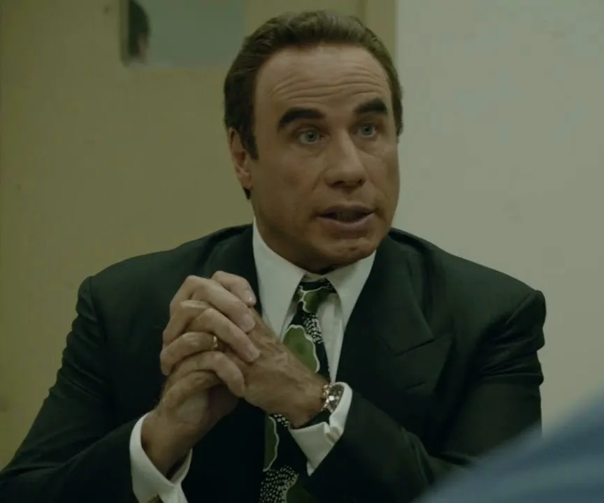 I don’t know who this person is, but they appear to be wearing a suit and tie, seated with hands clasped.
