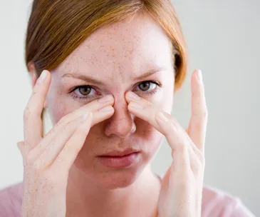 Woman gently massaging her under-eye area with her fingers to reduce dark circles.