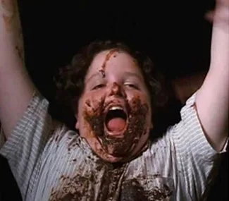 Bruce Bogtrotter from "Matilda" covered in chocolate cake, celebrating with arms raised.