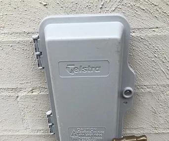 Telstra utility box installed with a tap mounted inside it on a wall.