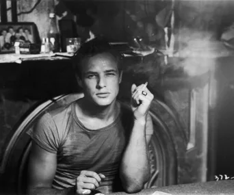 Black and white photo of Marlon Brando as Stanley Kowalski, wearing a T-shirt and holding a cigarette.
