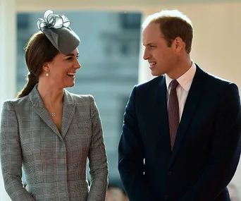 Prince and princess smiling at each other, both in formal attire, outdoors.