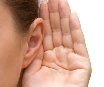 A person holding their hand to their ear, indicating they are listening closely.