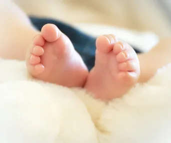 Baby's feet resting on a soft white blanket.