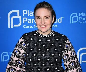 Person smiling in front of a Planned Parenthood backdrop, wearing a patterned sweater.