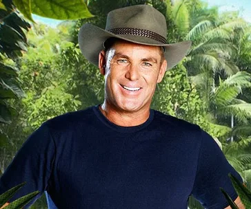 Man in a hat smiling in a tropical outdoor setting.