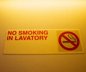 "No smoking in lavatory" sign with a cigarette icon crossed out in red circle.