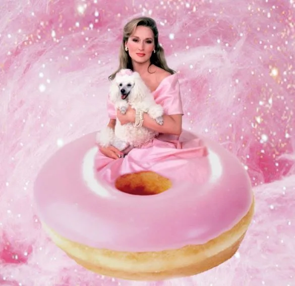 A woman in a pink dress holds a white poodle, sitting on a giant pink donut, with a sparkling pink background.