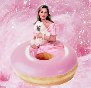 A woman in a pink dress holds a white poodle, sitting on a giant pink donut, with a sparkling pink background.