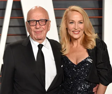 Couple posing at a formal event, man in a suit and woman in a black sequined dress with a smile.