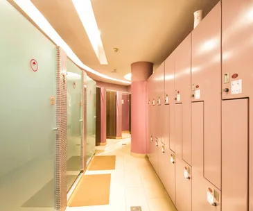 Modern locker room with purple lockers and frosted glass shower doors.