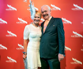 Two people smiling at a G.H. Mumm Champagne event, with a branded backdrop.