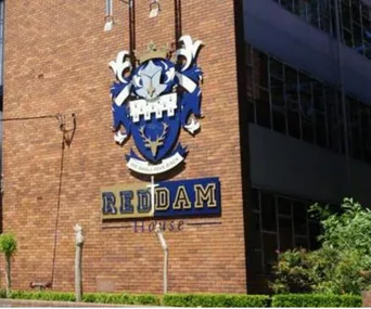 Reddam House school building with blue and white crest on brick wall.