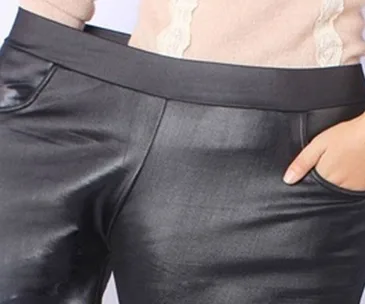 Close-up of black leather-like pants, hand in pocket, with part of a light sweater visible.