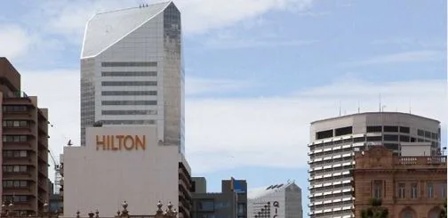 Brisbane cityscape with prominent Hilton Hotel building under a clear sky.