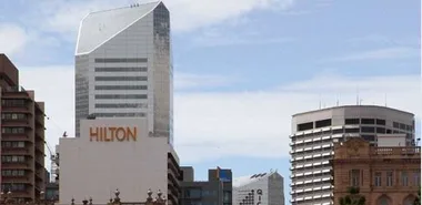 Brisbane cityscape with prominent Hilton Hotel building under a clear sky.