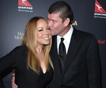 A woman smiles while a man in a suit kisses her on the cheek at a formal event.