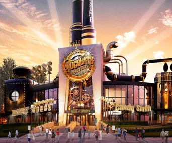 A whimsical chocolate factory with a golden sign, industrial pipes, and visitors under a warm sunset sky.
