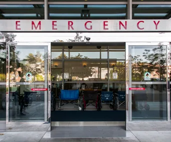 Hospital emergency room entrance with wheelchairs outside.