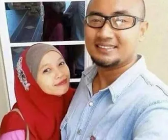 A couple taking a selfie with a smiling reflection of the woman appearing on the glass door behind them.