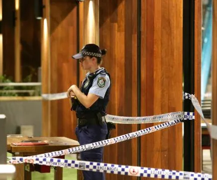 Police officer at crime scene in Westfield food court, with tape marking the area.
