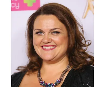 Chrissie Swan smiling at an event, wearing a black outfit and statement necklace.