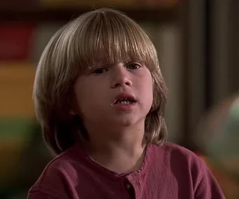 Young boy in a red shirt from a scene in the movie "Liar Liar," facing forward with a neutral expression.