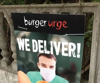 Burger Urge ad with a masked man holding a burger, text says "WE DELIVER!"