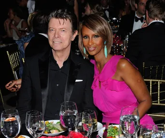 A couple sitting at a formal event, smiling, with a table set for dinner.