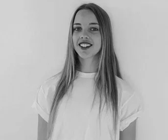 Young woman smiling, wearing a plain white T-shirt, with long straight hair in a black and white portrait.
