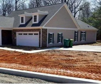 House with garage doors on second floor, leading to a steep drop instead of a driveway, highlighting a design flaw.