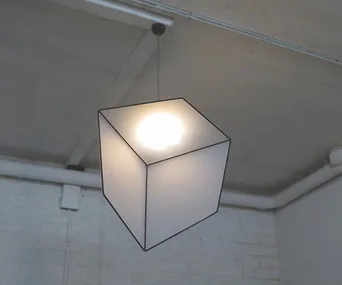 Suspended cube lamp with an optical illusion, appearing skewed due to its design.