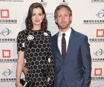 Anne Hathaway in a patterned dress with a man in a blue suit at a formal event, posing for the camera.