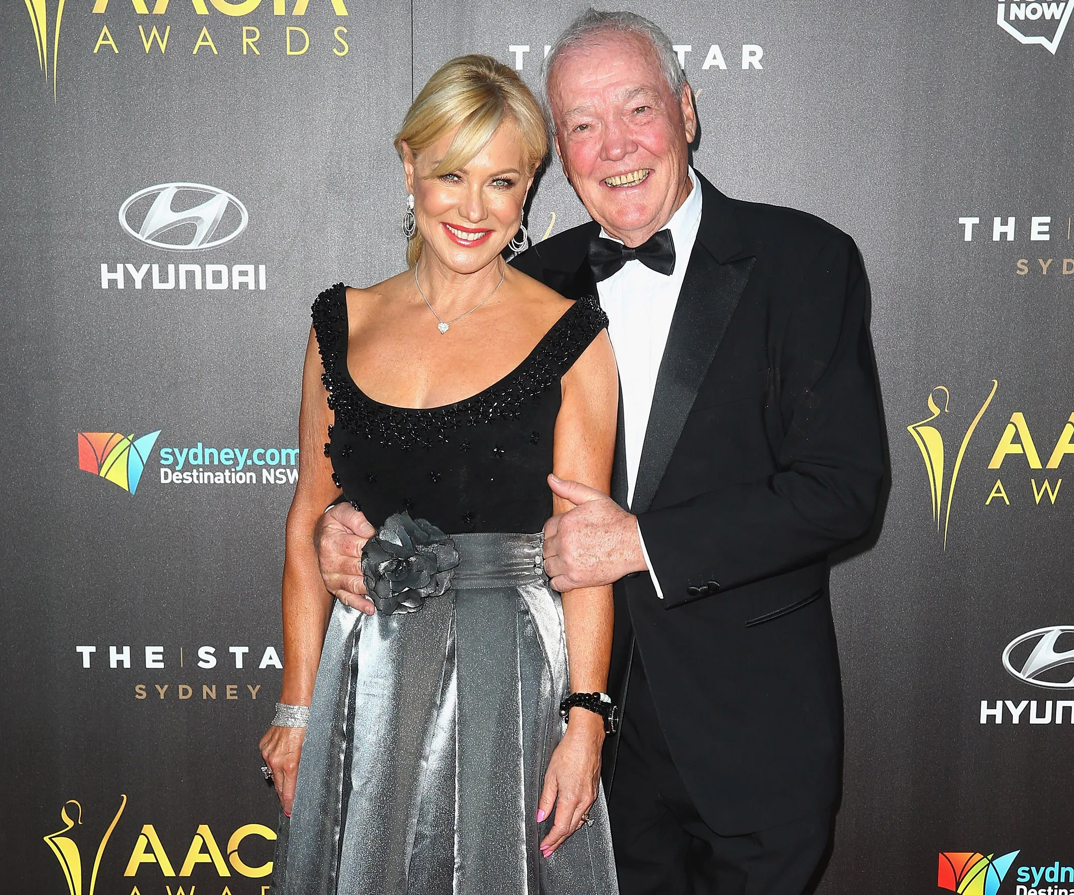 Couple smiling on the red carpet at the AACTA Awards in formal attire.