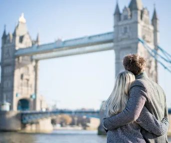 Couple embracing while looking at the Tower Bridge in London on a sunny day.