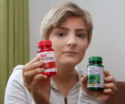 Young person holding bottles of slimming pills labeled "fat metaboliser" and "green tea extract."