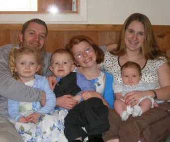 A family of five with three children and parents sitting together, with a mysterious figure in the mirror reflection above.
