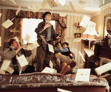 Harry stands in a living room while letters fly around, capturing a magical moment from a well-known film scene.