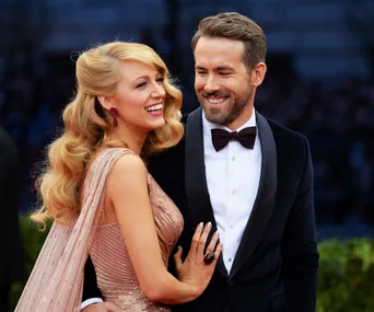 Couple smiling at a formal event, woman in a shimmering gown, man wearing a tuxedo.