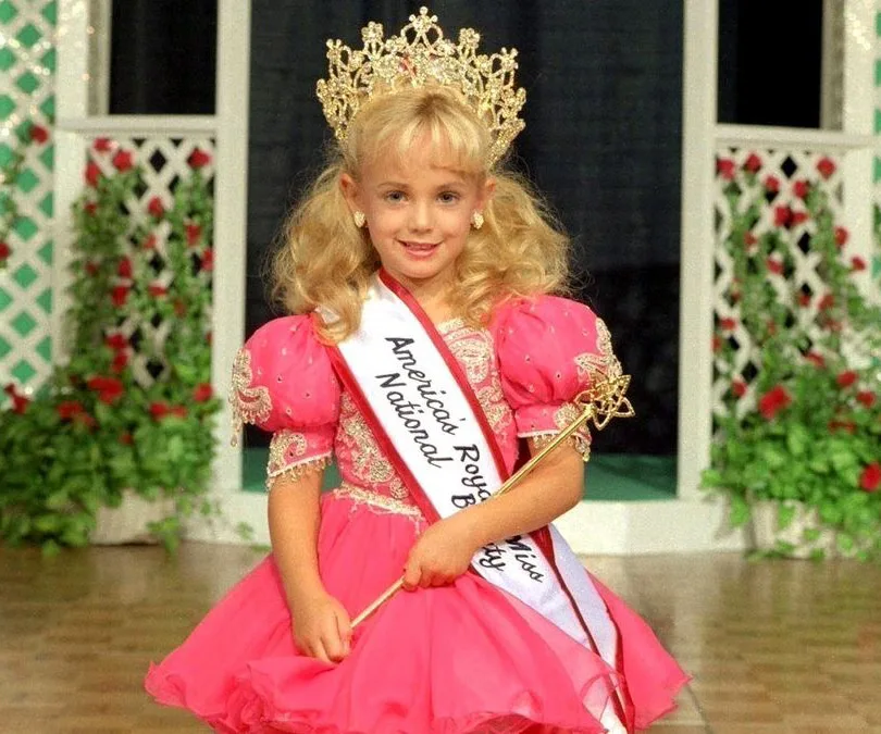 A young girl in a pageant dress and crown, wearing a sash labeled "America's Royal Miss National Beauty."